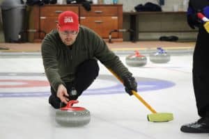 Photo of a curler releasing a stone during a bonspiel at the Norfolk, Connecticut, Curling Club.