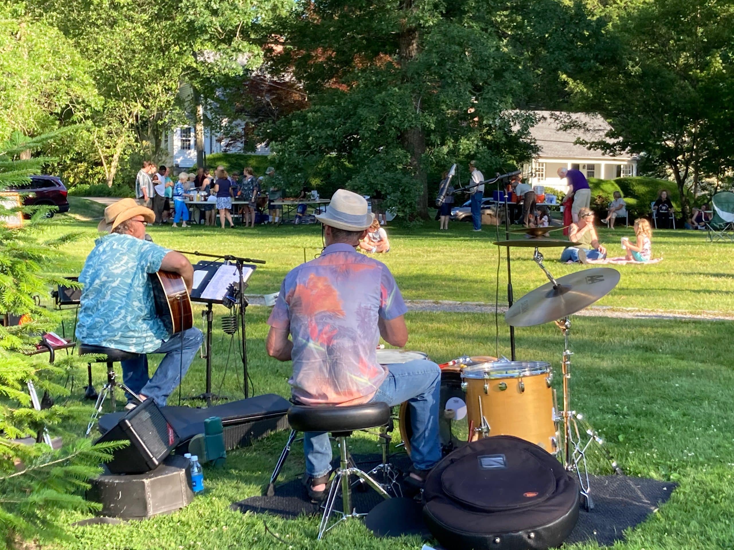 Photo of musicians playing at Friday Nights on the Green, with picnickers in the background.